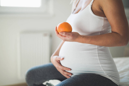 怀孕的女人手拿橙色