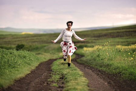 在乡村路上奔跑的快乐的妇女