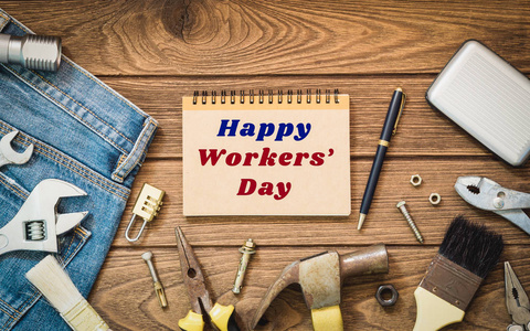国际工人一天背景概念   牛仔裤，很多方便的工具，笔记本与快乐工人一天文本，木制背景顶视图