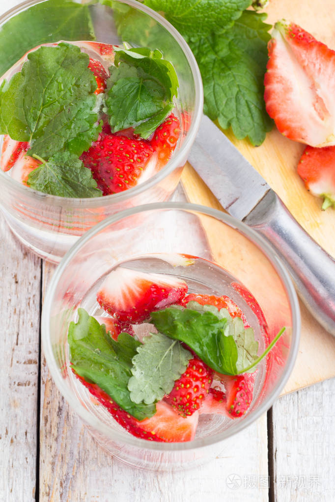 提神的饮料与草莓和薄荷在明亮的背景上