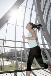 年轻美丽的竞技体育女人跑和慢跑穿过现代金属市桥