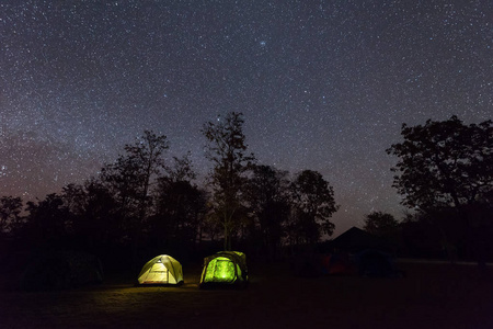 在繁星点点的夜空下的野营帐篷发光。