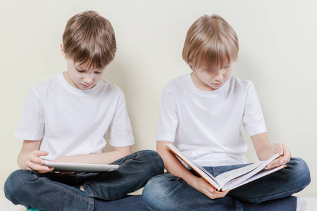 平板电脑和看书的孩子的男孩。孩子教育休闲概念