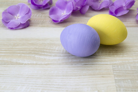 复活节彩蛋和紫色的花朵木制背景