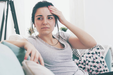 年轻人坐在舒适的沙发上担心头痛的女人