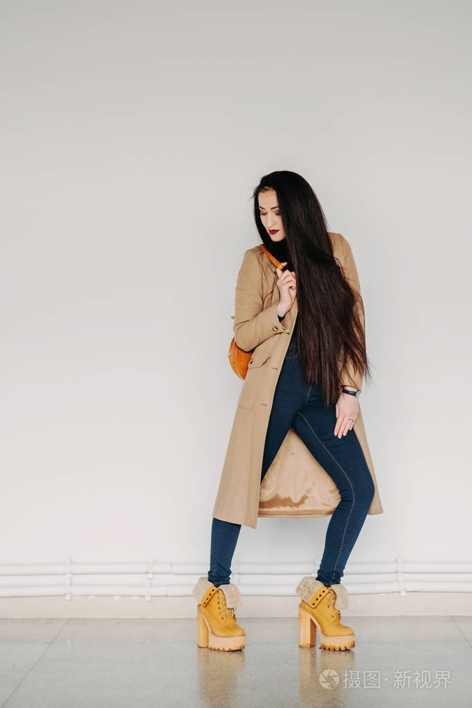 时尚概念: 全身肖像的巨大的灰色墙附近的年轻女孩.