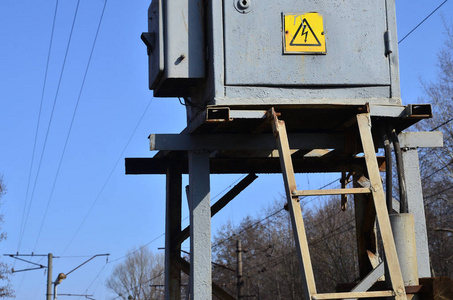 灰色电气变压器，标志警告铁路沿线附近有高压危险。提供电力的小型变电站