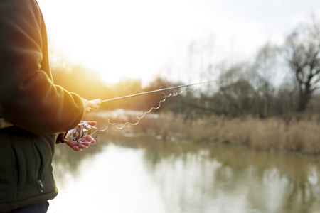 河里钓鱼。一位渔夫在河岸边钓鱼杆。男人渔夫捕到一条鱼