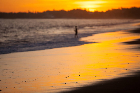 地处热带的海滩男孩渔夫的轮廓与落日