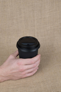 咖啡去杯在男人手中的粗麻布背景上