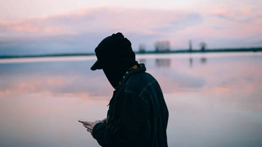 在海上背景上使用电话的人。一个欧洲人使用手机的特写镜头。浅对焦