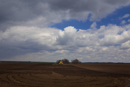 农业。拖拉机播种小麦早春在大草原的卡尔梅克在雷暴期间准备领域