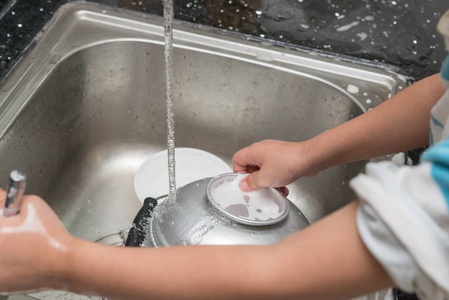 在厨房的水槽用肥皂海绵孩子洗餐具照片