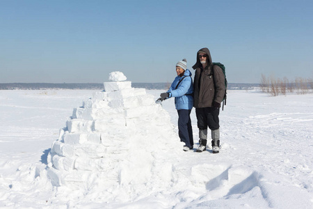 冬天, 男人和女人站在雪林上的冰屋前