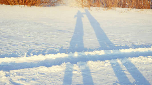 在冬日阳光明媚的日子里, 在日落的时候, 浪漫的情侣在雪地上徒步的