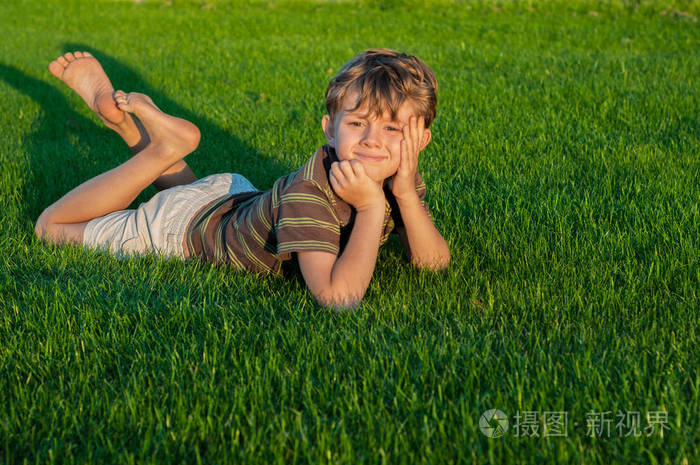 忧郁的小男孩躺在草坪上