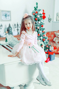 小女孩坐在一架白色的钢琴上