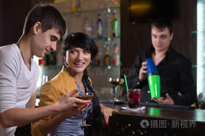 一对大笑的夫妇在酒吧柜台喝酒