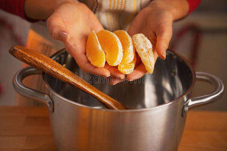 家庭主妇将橘子片放入锅中的特写镜头