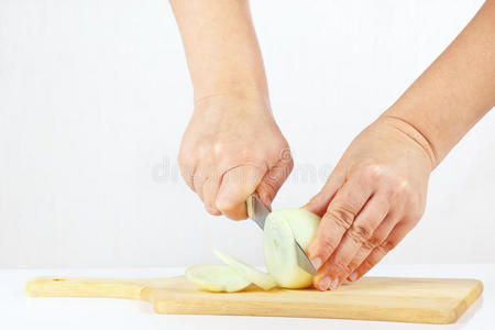 手拿刀在砧板上切洋葱