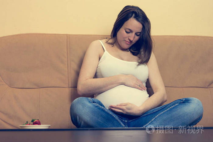 亲密肖像的年轻怀孕女子捧着她的肚子