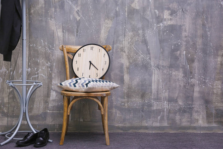 木椅上的背景灰色墙上的时钟与枕头