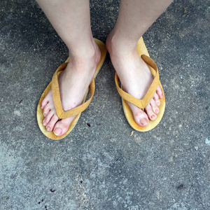 地面背景上女性脚上的黄色凉鞋