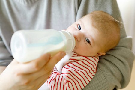 父亲与护理瓶中的牛奶喂养刚出生的婴儿女儿