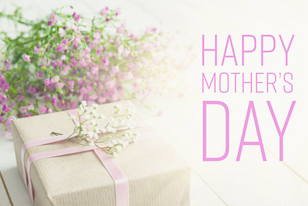 母亲节的背景，白色的木桌上粉红色的花朵和一份礼物