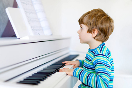 漂亮的孩子小男孩弹钢琴在客厅或音乐学校