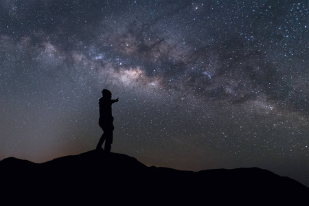 银河景观。剪影男子砰，站在夜晚的天空和明亮的星星，在背景上山顶