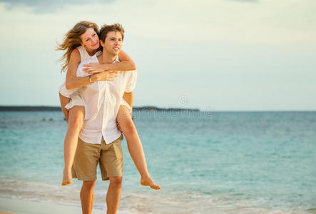 一对相爱的年轻夫妇日落时在海滩上散步