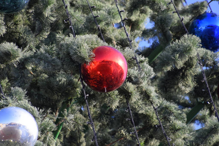 装饰新年树。 站在露天的圣诞树上的金属玩具球和其他装饰品。