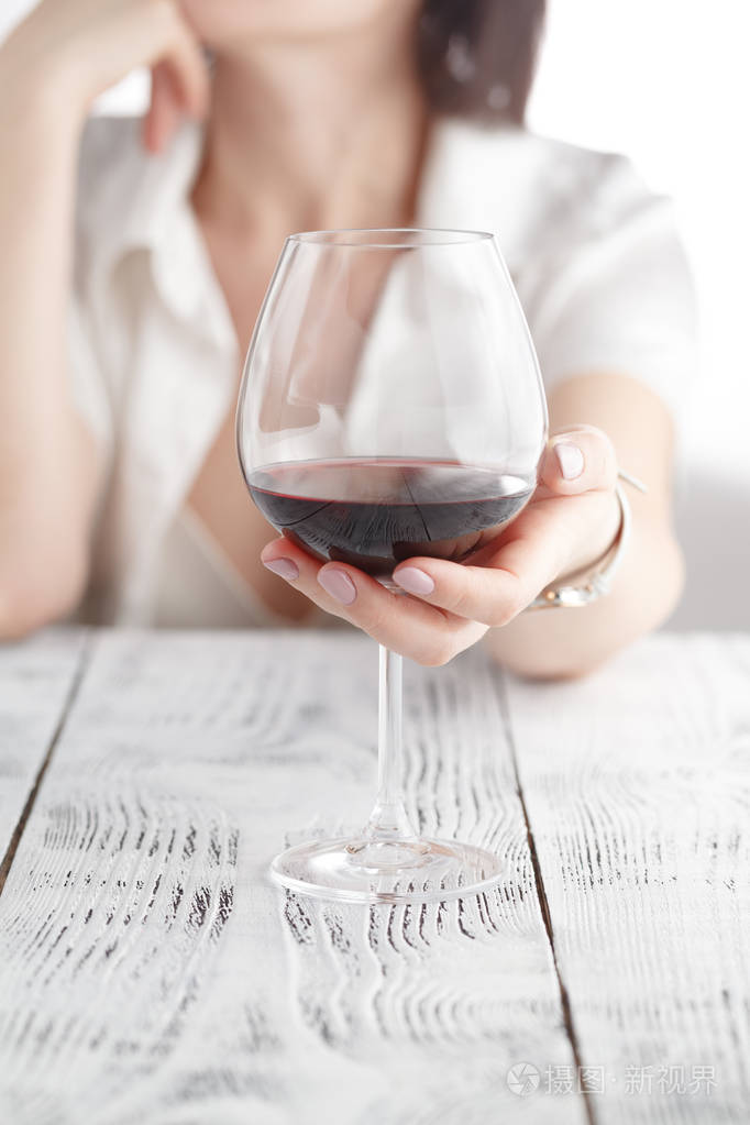 在白色背景上喝酒的女人专注于葡萄酒杯
