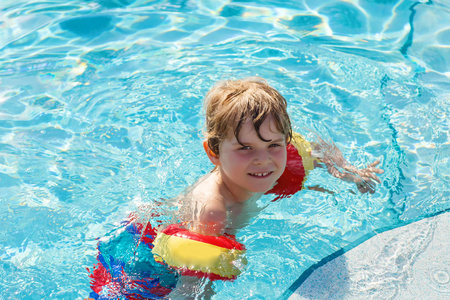 快乐的小小孩的男孩,在游泳池玩乐照片