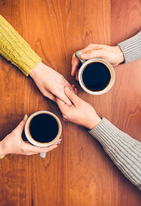 人们从杯子里喝咖啡，牵手的浪漫的约会。夫妇在爱情上日期