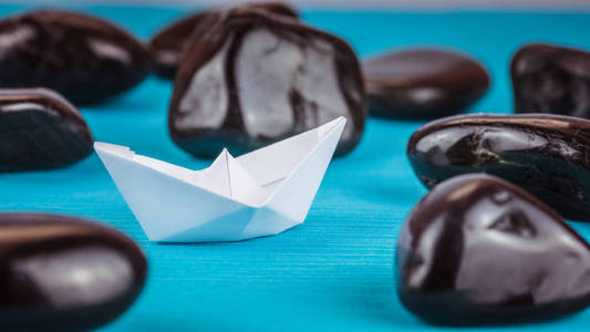 一个白皮书舰船之间的抽象的黑色岩石石头在蓝色背景