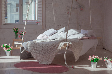 经典的斯堪的纳维亚风格的白色阁楼内政。挂床吊在天花板。舒适大折叠米色格子，巨型织毯，臂针织。时尚的室内设计