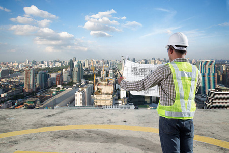 看看规划建设项目与城市景观背景蓝图的建筑工程师照片