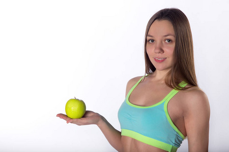 年轻的健身女孩姿势与苹果和哑铃