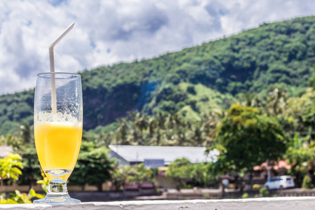 杯橙汁与棕榈树，户外亮热带模糊背景上。热带巴厘岛印度尼西亚