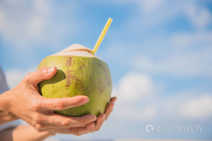 椰子在手中的妇女和蓝蓝的天空背景