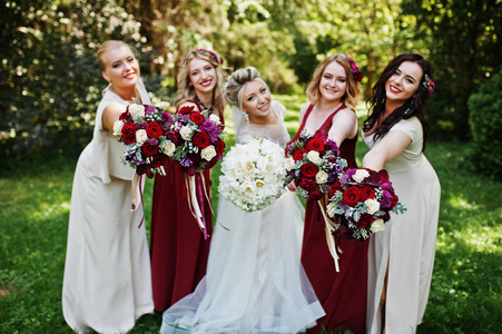 华丽的金色新娘与四个伴娘在红色和米色相间的衣服