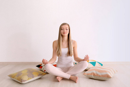 美丽的年轻女子坐在家里的地板上睡前冥想照片