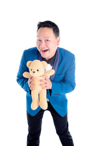 穿着蓝色西装的亚洲男人抱着泰迪熊，微笑着看着白色