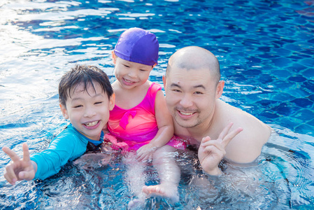亚洲父亲和他的孩子在游泳池里