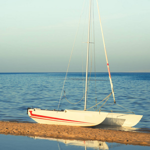 在平静的海面上海滩的白色帆船游艇