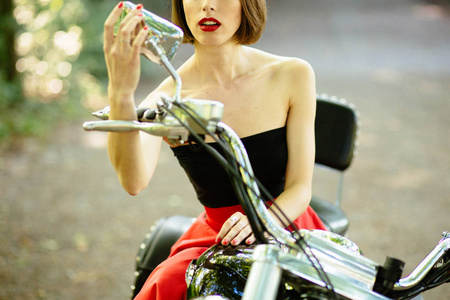 美丽的女孩骑摩托车在构成附近她摩托车后视镜有魅力的女人骑自行车的人看