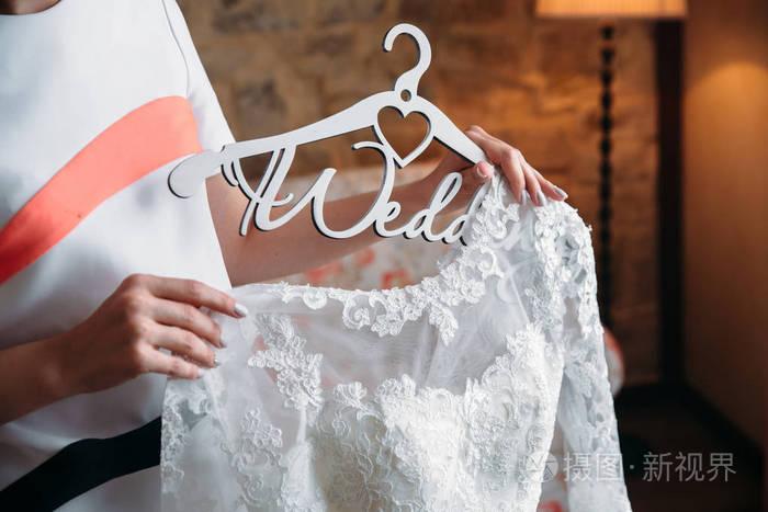 新娘抱着一件衣服挂在衣架上