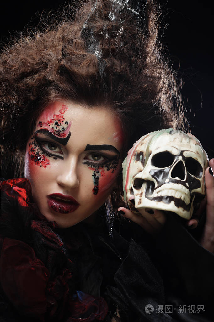 年轻漂亮的女巫抱着一个骷髅头